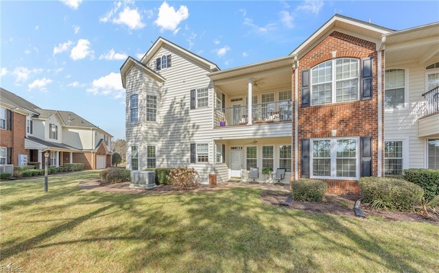 back of house featuring brick siding, a lawn, a balcony, and central AC unit