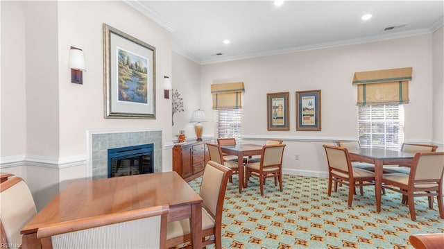 dining space featuring a tile fireplace, visible vents, crown molding, and baseboards