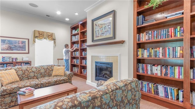 living area with recessed lighting, visible vents, built in features, ornamental molding, and a tiled fireplace