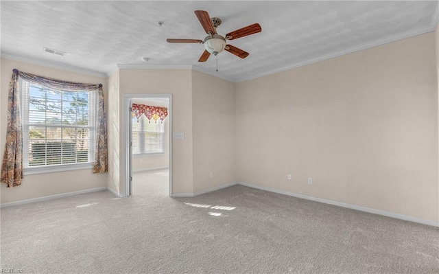 carpeted spare room featuring ornamental molding, a ceiling fan, visible vents, and baseboards