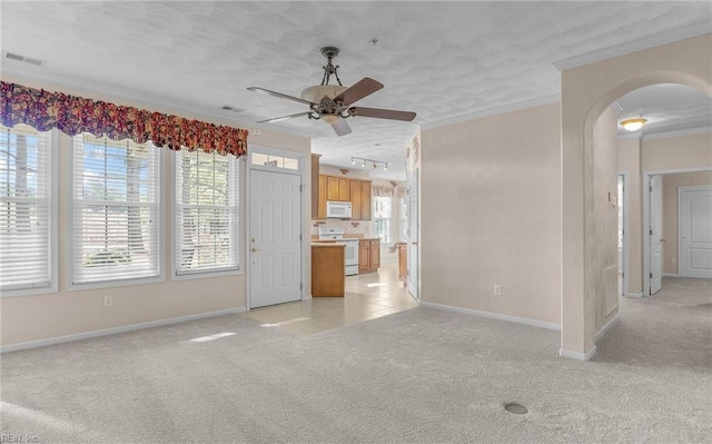 unfurnished living room featuring ornamental molding, arched walkways, light carpet, and visible vents