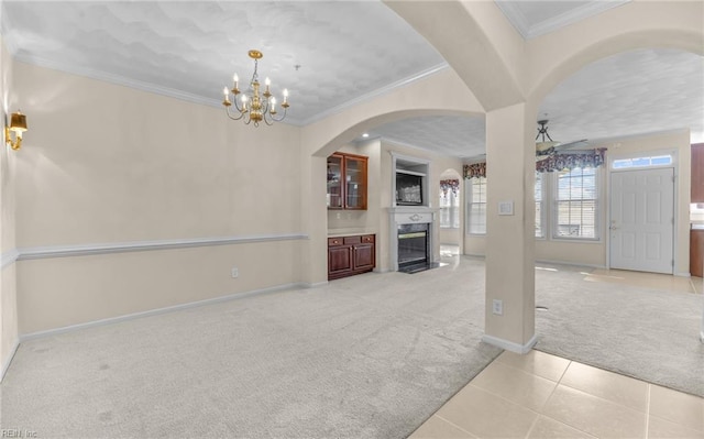 unfurnished living room with carpet, ornamental molding, a high end fireplace, tile patterned flooring, and baseboards