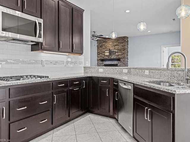 kitchen featuring stainless steel appliances, pendant lighting, a sink, and a peninsula