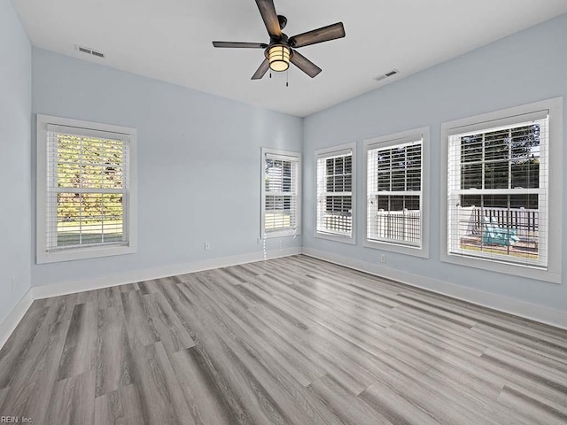 unfurnished room featuring light wood-style floors, baseboards, visible vents, and a ceiling fan