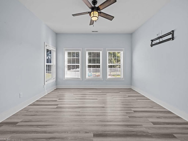 empty room featuring visible vents, light wood finished floors, a ceiling fan, and baseboards