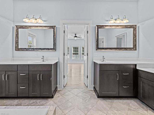 full bathroom featuring a sink, a ceiling fan, baseboards, and two vanities