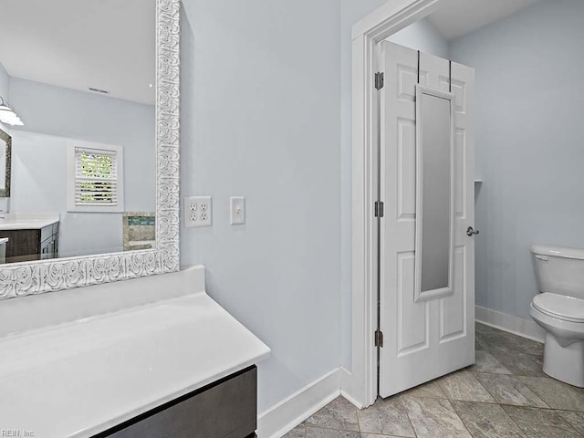 bathroom with toilet, vanity, and baseboards