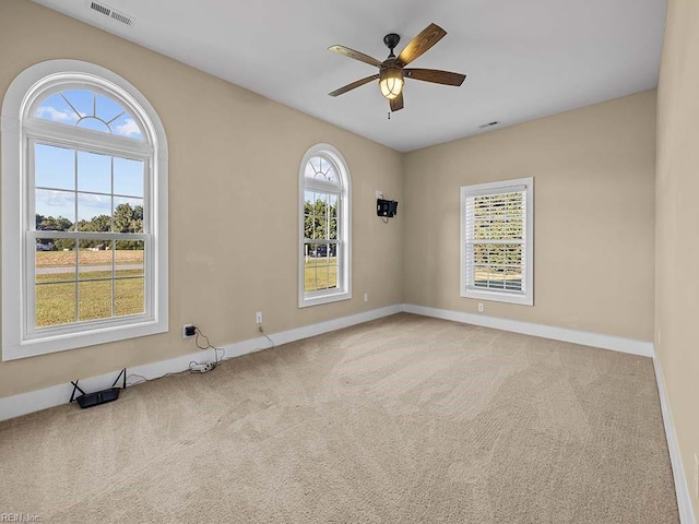 spare room with a ceiling fan, carpet flooring, visible vents, and baseboards