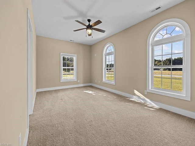 carpeted spare room with baseboards, visible vents, and ceiling fan