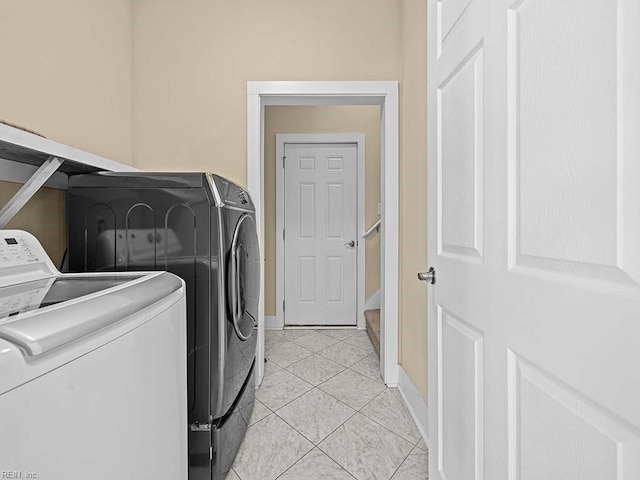 laundry area featuring laundry area, baseboards, washer and clothes dryer, and light tile patterned flooring