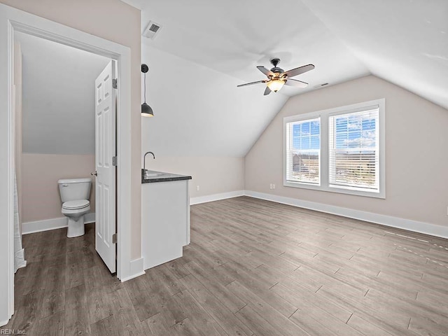 bonus room featuring baseboards, visible vents, ceiling fan, wood finished floors, and vaulted ceiling