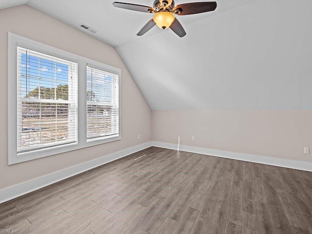 bonus room with lofted ceiling, visible vents, baseboards, and wood finished floors