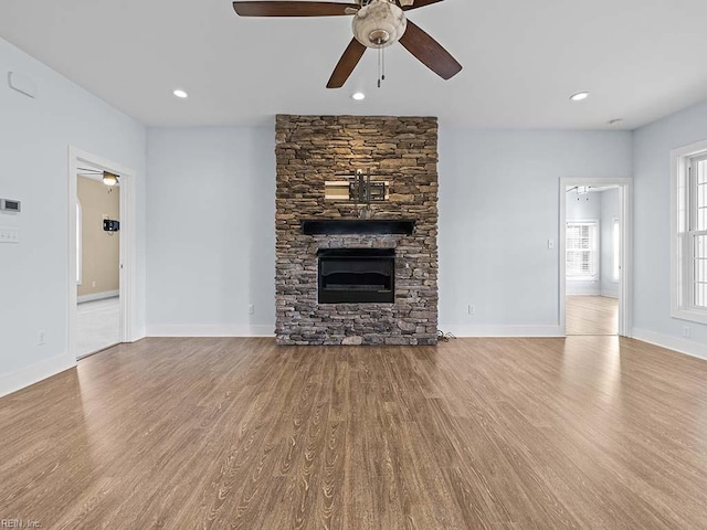 unfurnished living room with a ceiling fan, light wood-type flooring, a stone fireplace, and recessed lighting