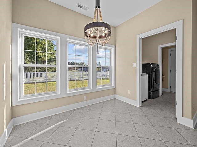 unfurnished dining area featuring a notable chandelier, light tile patterned floors, visible vents, independent washer and dryer, and baseboards