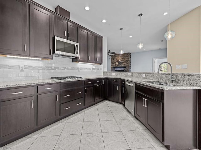 kitchen featuring dark brown cabinetry, stainless steel appliances, a peninsula, a sink, and hanging light fixtures