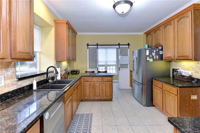 kitchen with stainless steel appliances, brown cabinets, a sink, and a barn door