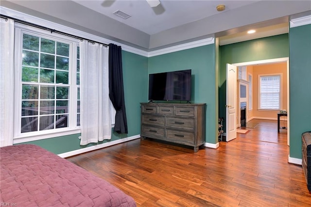 bedroom featuring a ceiling fan, visible vents, baseboards, and wood finished floors