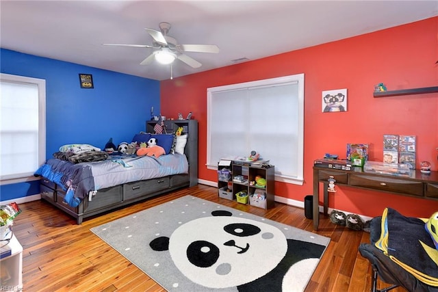 bedroom featuring a ceiling fan, baseboards, visible vents, and hardwood / wood-style floors