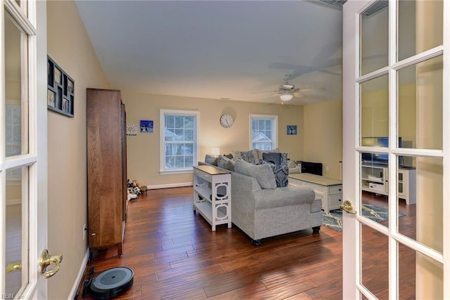 living area featuring french doors, dark wood-style flooring, a ceiling fan, and baseboards