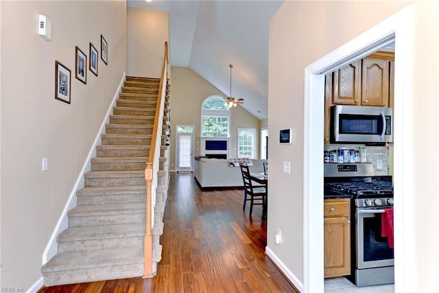 interior space featuring ceiling fan, stainless steel appliances, wood finished floors, open floor plan, and dark countertops