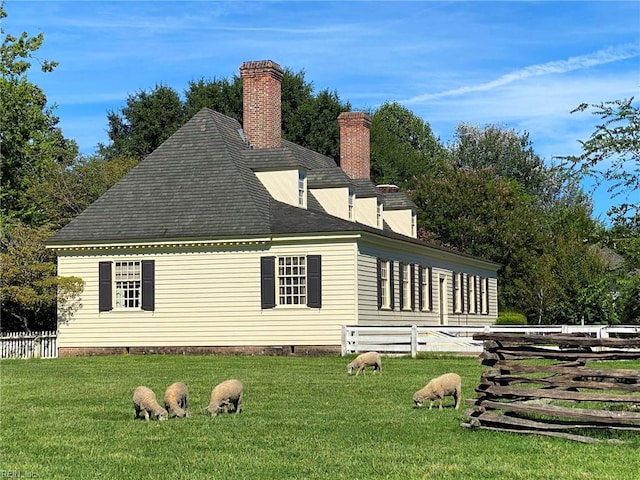 exterior space with a lawn, a chimney, and fence