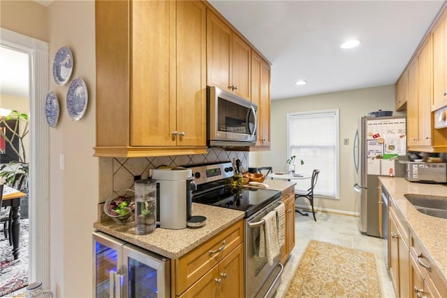 kitchen featuring wine cooler, stainless steel appliances, decorative backsplash, a sink, and light stone countertops