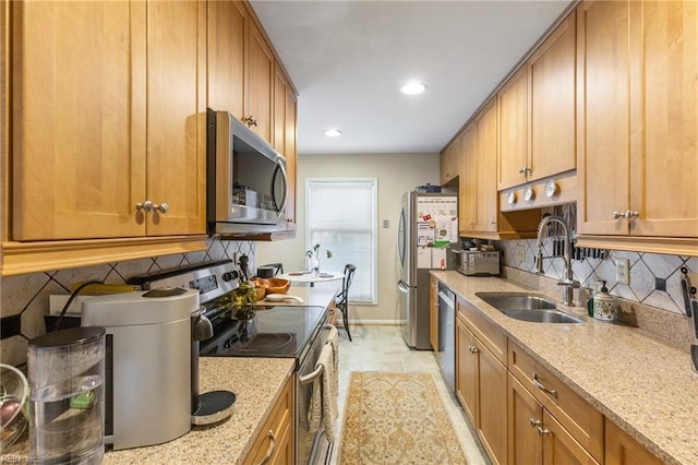 kitchen with light stone counters, a sink, appliances with stainless steel finishes, brown cabinets, and tasteful backsplash