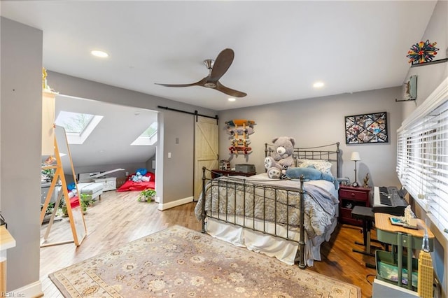 bedroom with a skylight, a barn door, wood finished floors, and recessed lighting