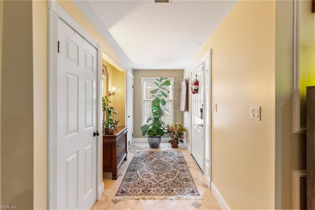 doorway featuring baseboards and light tile patterned flooring