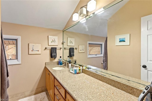 bathroom with baseboards, vaulted ceiling, and vanity