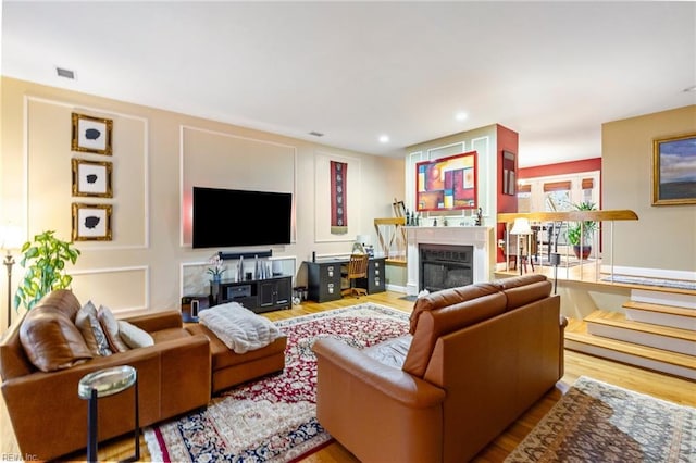 living area featuring recessed lighting, visible vents, wood finished floors, and a glass covered fireplace