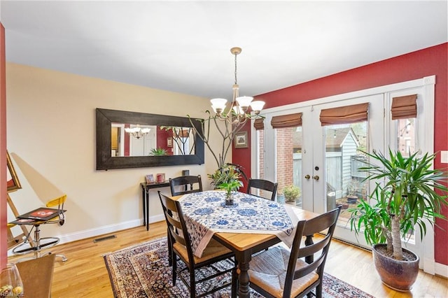 dining space with baseboards, visible vents, a chandelier, and wood finished floors