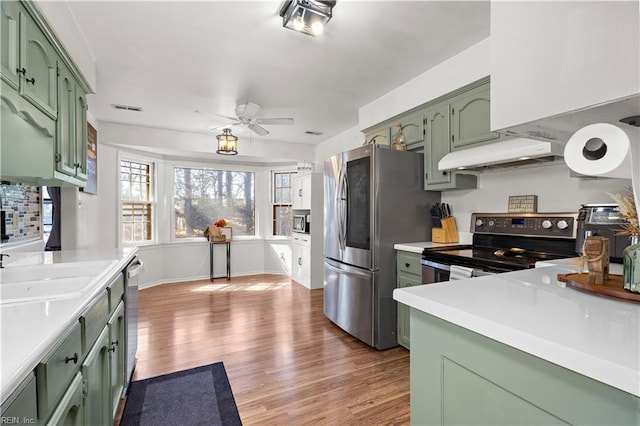 kitchen featuring stainless steel appliances, green cabinets, and light countertops