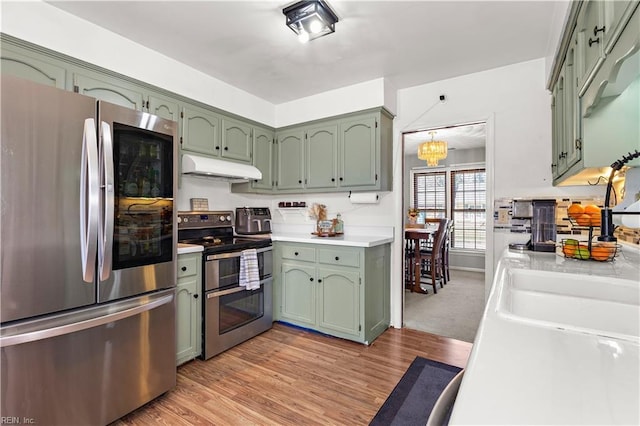 kitchen featuring under cabinet range hood, green cabinetry, stainless steel appliances, and light countertops