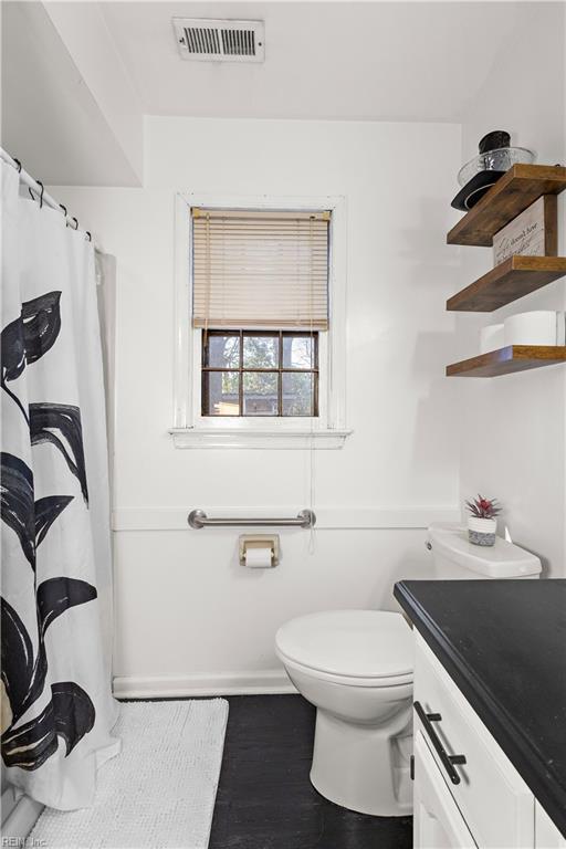 bathroom featuring visible vents, toilet, vanity, wood finished floors, and baseboards