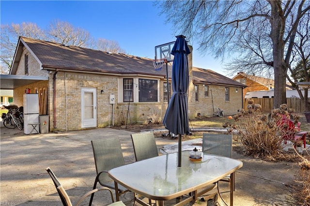 rear view of property with brick siding, a patio, and fence