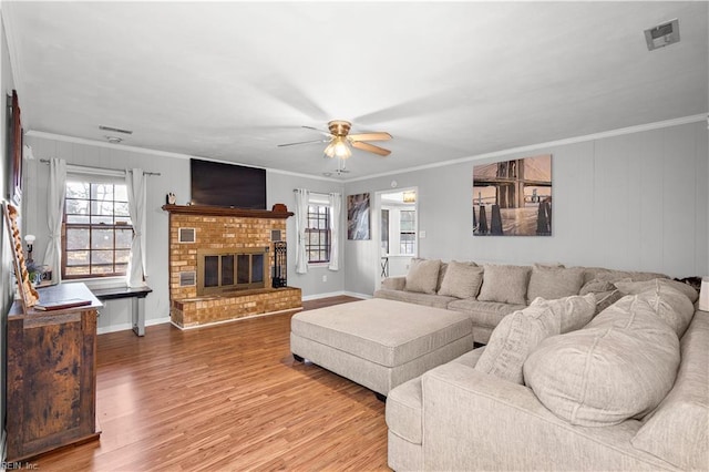 living room with a brick fireplace, crown molding, and wood finished floors