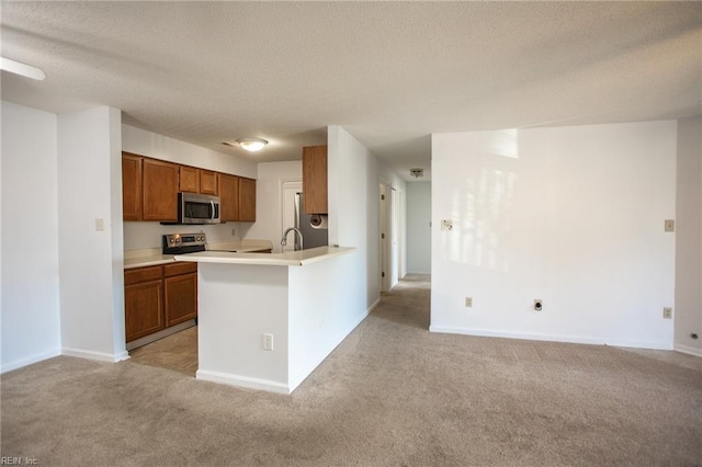 kitchen featuring light carpet, light countertops, appliances with stainless steel finishes, and brown cabinetry