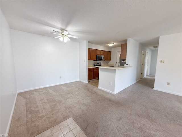 kitchen featuring a textured ceiling, light carpet, open floor plan, light countertops, and stainless steel microwave