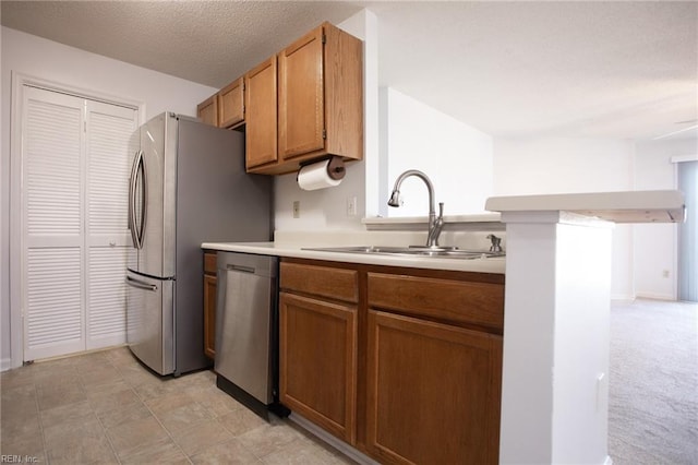 kitchen featuring a textured ceiling, a sink, light countertops, brown cabinets, and dishwasher