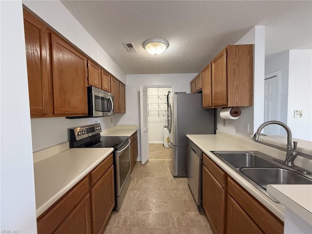 kitchen with appliances with stainless steel finishes, light countertops, visible vents, and a sink