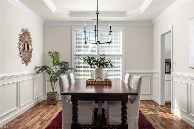 dining area with a tray ceiling, wood finished floors, and a notable chandelier