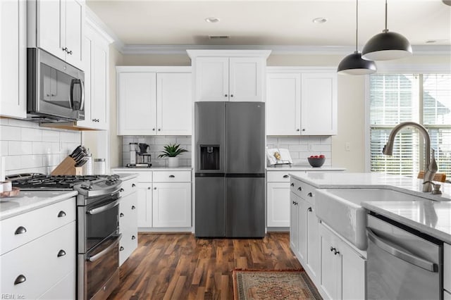 kitchen with appliances with stainless steel finishes, a sink, white cabinetry, and crown molding