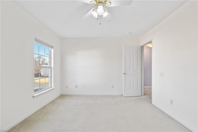 spare room with light carpet, baseboards, and a ceiling fan