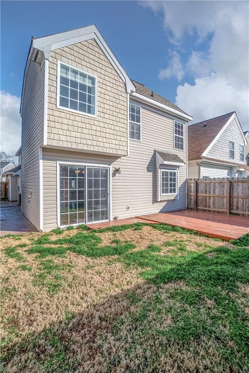 rear view of house with a lawn, a deck, and fence