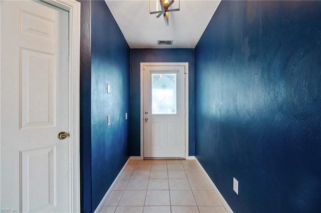 doorway with baseboards, visible vents, and light tile patterned flooring