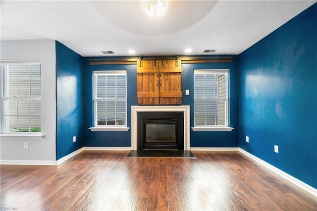 unfurnished living room featuring visible vents, baseboards, dark wood finished floors, and a fireplace with flush hearth