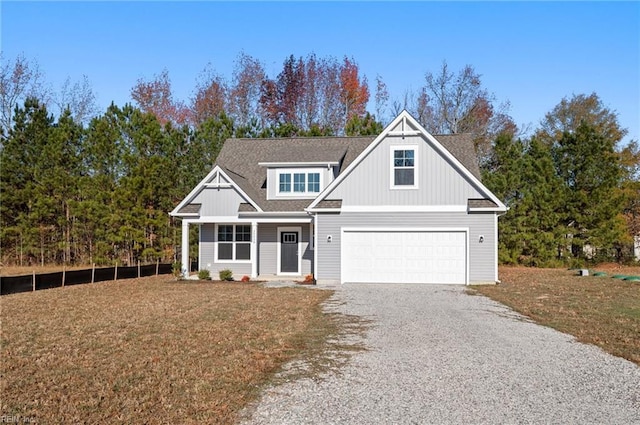 view of front of house with gravel driveway, a garage, a front lawn, and roof with shingles