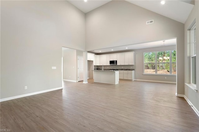 unfurnished living room featuring a chandelier, light wood-style flooring, recessed lighting, visible vents, and baseboards