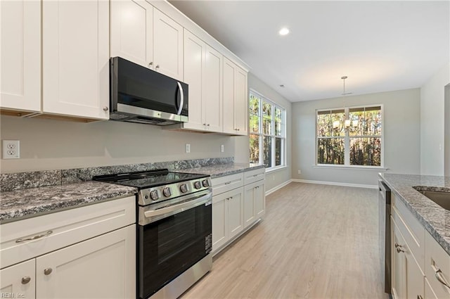 kitchen featuring light stone counters, light wood-style flooring, stainless steel appliances, baseboards, and white cabinets